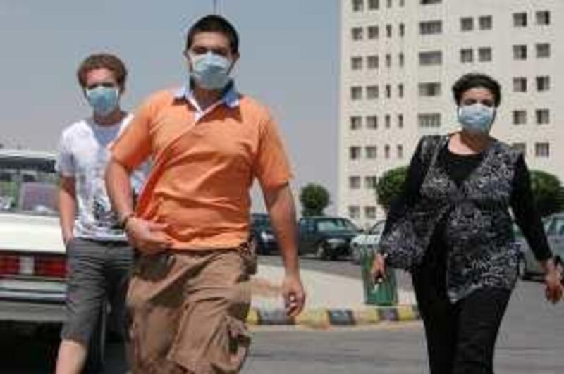 People wearing masks walk in Amman  June 17, 2009. Jordan, Qatar and Yemen have identified their first cases of the H1N1 flu virus in five young patients who had recently arrived from the United States and Austria. REUTERS/Muhammad Hamed (JORDAN HEALTH)