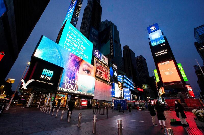 People walk round Times Square as some screens are illuminated in blue as part of the "Light It Blue" initiative to honor healthcare workers, during the outbreak of the coronavirus disease (COVID-19), in New York City, New York, U.S. April 23, 2020. REUTERS/Eduardo Munoz