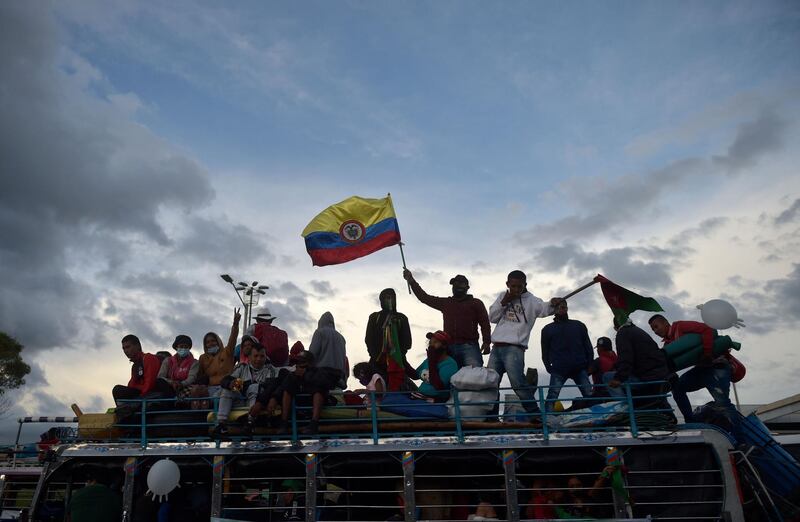 Colombian indigenous people flutter a Colombian flag as they arrive in Bogota on a "chiva" -local transport vehicle- in the framework of a "Minga" (indigenous meeting) to demand a meeting with Colombian President Ivan Duque.  AFP