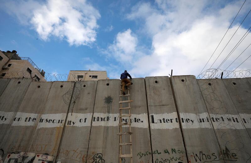 A Palestinian uses a ladder to climb over a section of the Israeli barrier as he tries to make his way to attend the first Friday prayers of Ramadan in Jerusalem's Al Aqsa mosque. Reuters