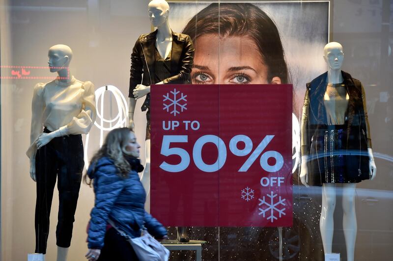 A woman walks past a poster announcing 50 percent sale is seen at the window display of a shop in Beirut, Lebanon. EPA