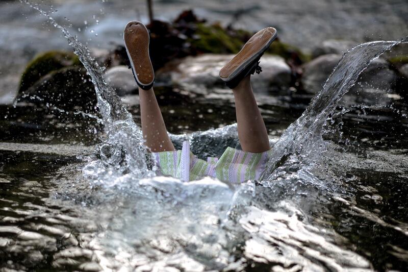 A participant's feet show after jumping into cold water, wearing a Dirndl dress, of the Grundlseer Traun river in Bad Aussee, Austria. EPA