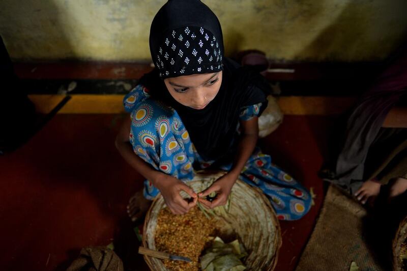 Twelve year old Indian villager Tarannum Alvi sits with materials as she tries to roll bidi's in Kannauj.