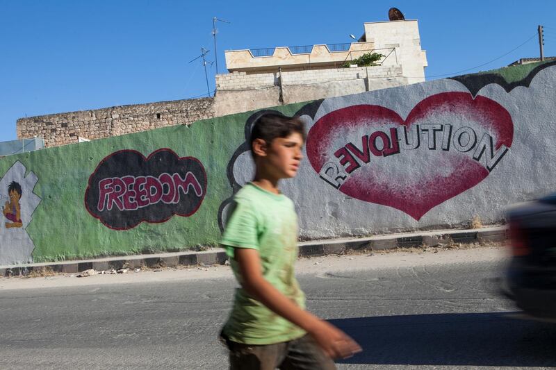 A Syrian boy walks past graffiti in the village of Kafranbel in the northwestern province of Idlib.  AFP