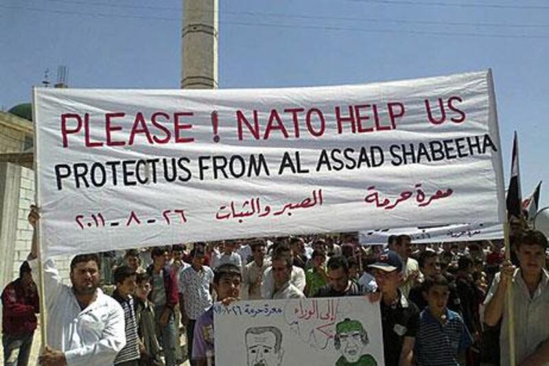 In this citizen journalism image provided by Shaam News Network, anti-Assad protesters call for help from Nato during a demonstration at Maaret Harma village, Edlib province on Friday.
