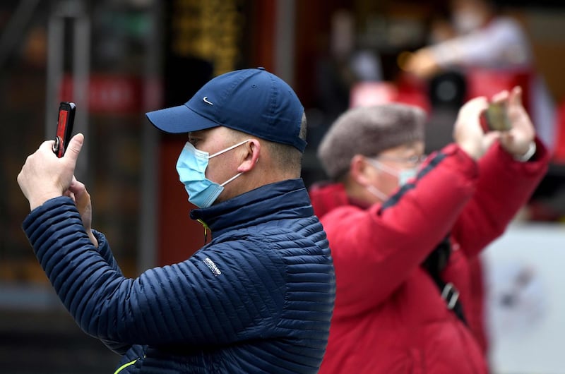 People wearing protective facemasks use their mobile phones in Yu Park in Shanghai. AFP