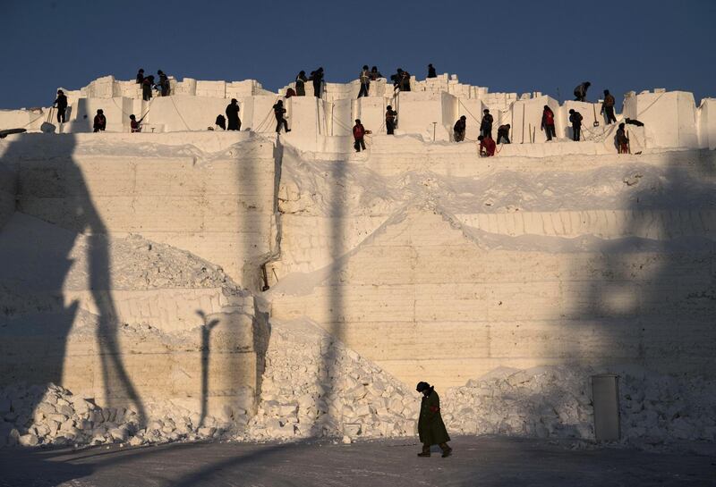 A team of Chinese labourers carve into a large snow mound in preparation for the Harbin Ice and Snow Festival in Harbin, China. Getty Images