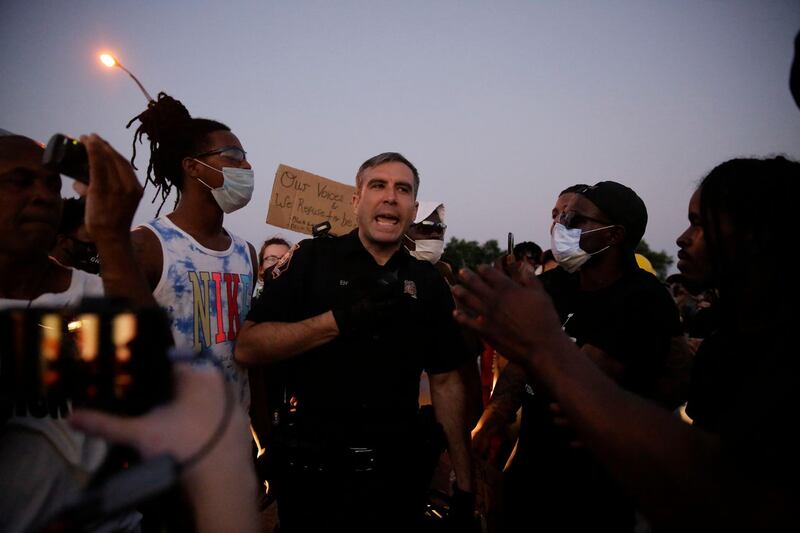 An officer talks with protesters near the Atlanta Wendy's where Rayshard Brooks was shot and killed by police. AP