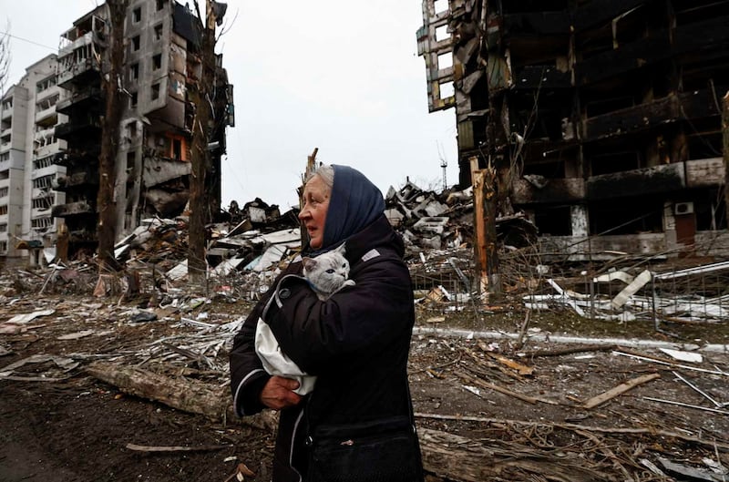A woman carries her cat as she walks past buildings that were destroyed by Russian shelling, in Borodyanka. Reuters