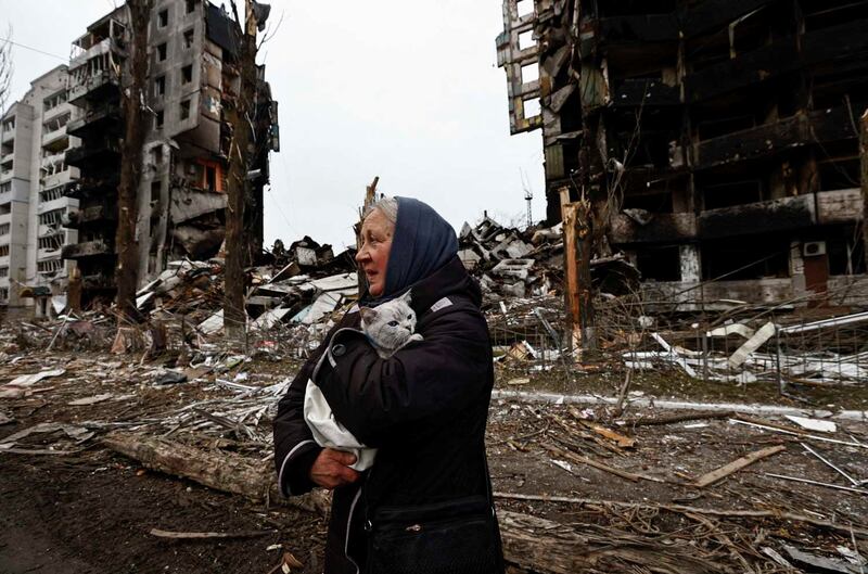 A woman carries her cat past buildings destroyed by Russian shelling in Borodyanka, in the Kyiv region of Ukraine. Reuters