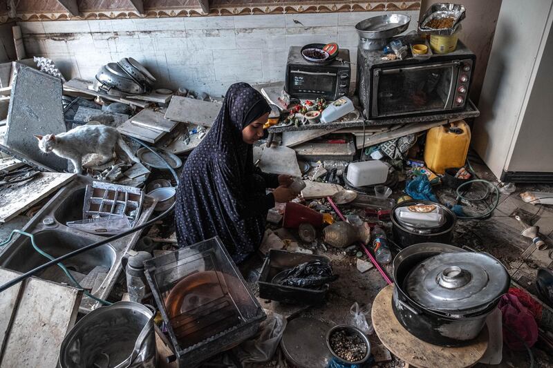 A Palestinian woman and a cat sit in a ruined kitchen in a home in Beit Hanoun, northern Gaza, on May 22, 2021. Getty