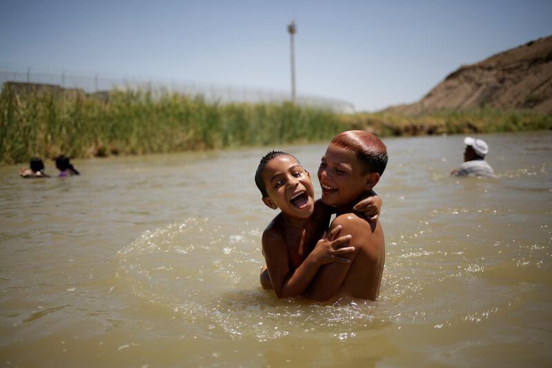 Children cool off during a hot day on the Mexican side of the Rio Bravo near the fence marking the border between Mexico and the US, as pictured from Ciudad Juarez. Reuters