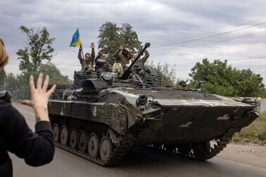 In this photograph taken on September 20, 2022 a local resident greets Ukrainian soldiers riding an armoured personnel carrier in Mala Komyshuvakha, near Izyum, Kharkiv region.  (Photo by Yevhen TITOV  /  AFP)