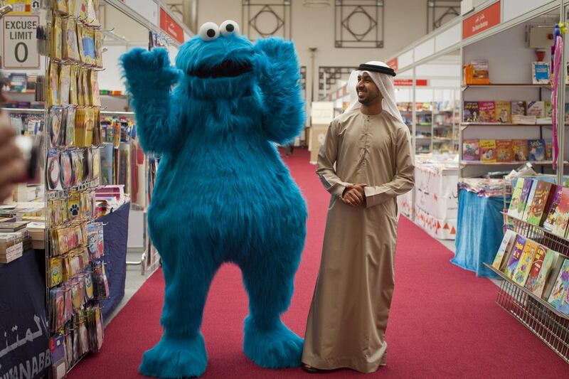 The creative director of the new version of Iftah Ya Sim Sim, Abdalla Al Sharhan, with the Sesame Street muppet Cookie Monster, known as Kaaki in the Arab version, at the Al Ain Reads Bookshow. Razan Alzayani / The National