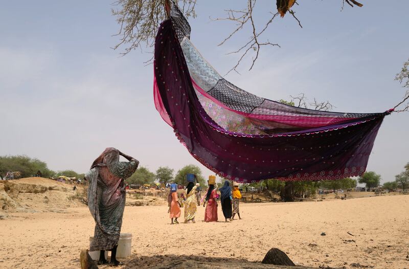 Women who fled the conflict in Sudan's Darfur region, and were previously internally displaced, carry water at a refugee camp in Borota, Chad. Reuters