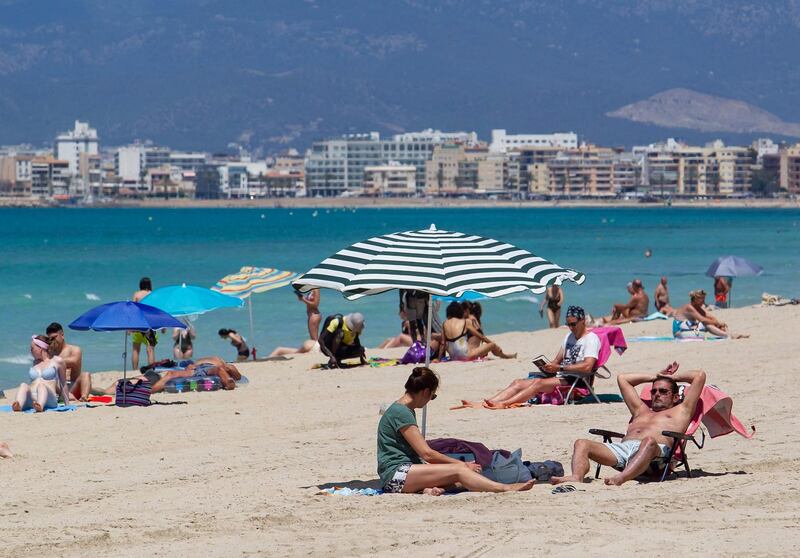 Tourists sunbathe at Palma Beach in Palma de Mallorca in Spain. Spain opened its borders to vaccinated travellers from all over the world, hoping an influx of visitors will revitalise its all-important tourism sector. AFP