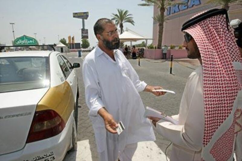 Mashahoor Afzal, a Pakistan taxi driver, asks Jaber al Braiki, not to give him a fine outside Marina Mall yesterday.