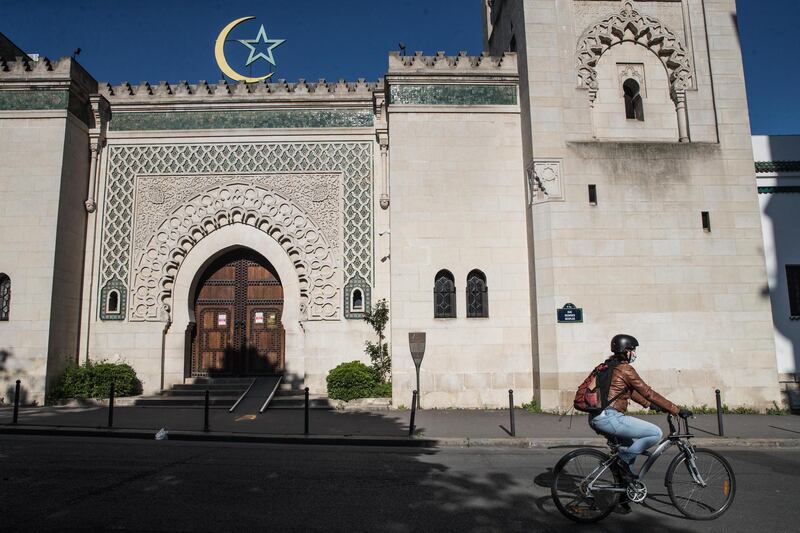 A woman wearing a protective mask rides her bike next to the Great Mosque of Paris, France.  EPA