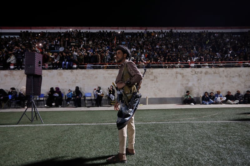 A Houthi militiaman stands guard as Yemenis watch the final of the West Asian Junior Championships between Yemen and Saudi Arabia. EPA