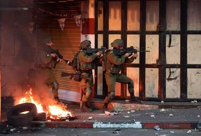 Israeli soldiers take aim during clashes with Palestinian protesters in the city center of Hebron in the occupied West Bank, following a rally for Fateh movement supporters denouncing the Israeli Gaza attacks and supporting Palestinians of Jerusalem, on May 14, 2021. / AFP / HAZEM BADER
