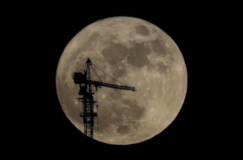 A tower crane is silhouetted against the supermoon in Dubai. Kamran Jebreili / AP Photo