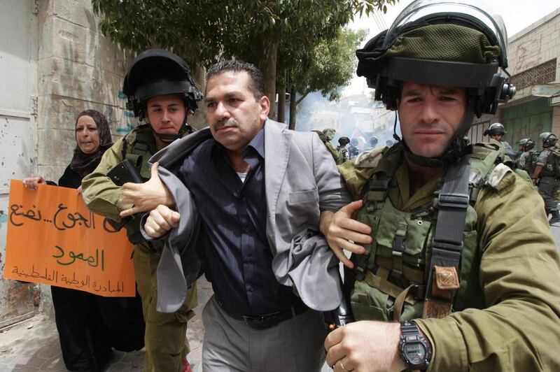 Israeli soldiers detain a Palestinian demonstrator during a protest against Israeli settlements and in support of Palestinian inmates held in Israeli jails who are in hunger strike, on June 5, 2014 near the Israeli settlement of Beit Romano in the centre of the divided West Bank Palestinian city of Hebron. Hazem Bader/AFP Photo