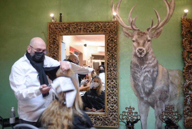 Hairdresser Marco Trapani colours the hair of a client at his hair salon reopening in Dortmund. AFP