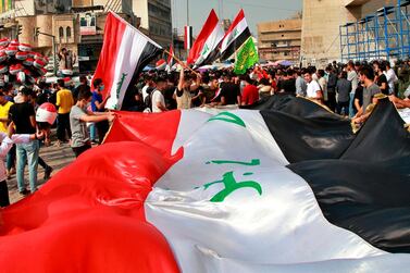 Protesters hold Iraqi flags in Tahrir Square during a demonstration this month calling for the government to resign, in Baghdad, Iraq. AP