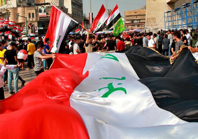 Protesters hold Iraqi flags in Tahrir Square during a demonstration calling for the government to resign, in Baghdad, Iraq, Sunday, Nov. 8, 2020. (AP Photo/Khalid Mohammed)