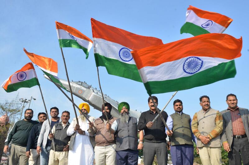 Bharatiya Janata Party activist wave Indian national flags in front of a fighter plane model as they celebrate the Indian Air Force (IAF) strike launched on a Jaish-e-Mohammad (JeM) camp at Balakot, at the Punjab state war heroes memorial and museum, in Amritsar on February 26, 2019. Indian warplanes breached Pakistani airspace on February 26 in a move that sent tensions over disputed Kashmir spiralling, but Islamabad furiously denied claims the strike destroyed a militant camp and inflicted heavy casualties. / AFP / NARINDER NANU
