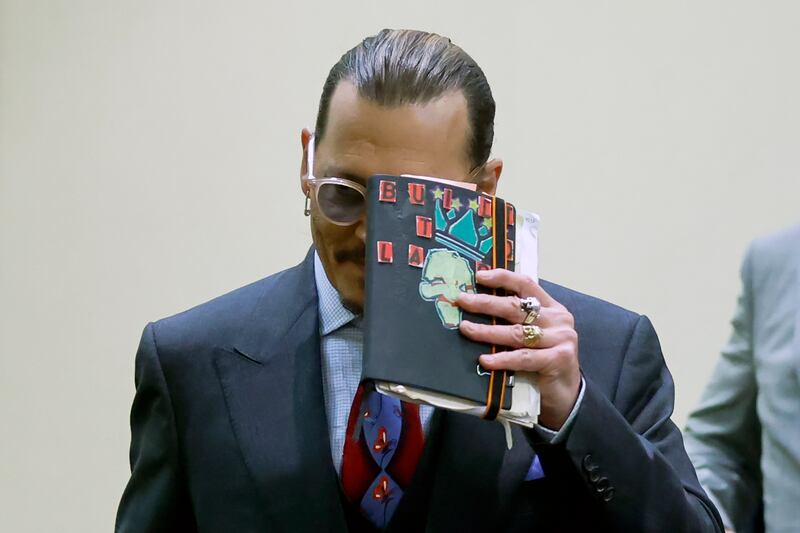 Actor Johnny Depp holds up his notebook, which appears to have a picture of the late rapper Biggie Smalls on the cover, during his defamation trial against his former wife Amber Heard. AP