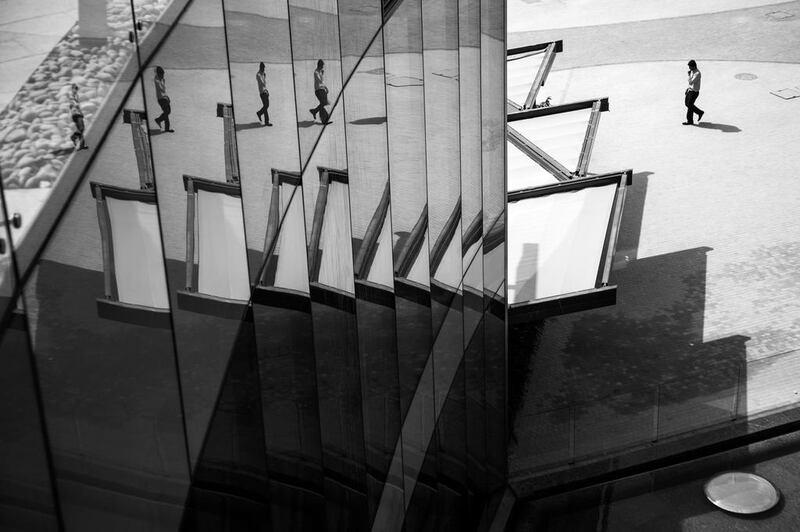 A man is reflected in the glass walls of a building on Al Maryah Island, Abu Dhabi. Brian Kerrigan / The National