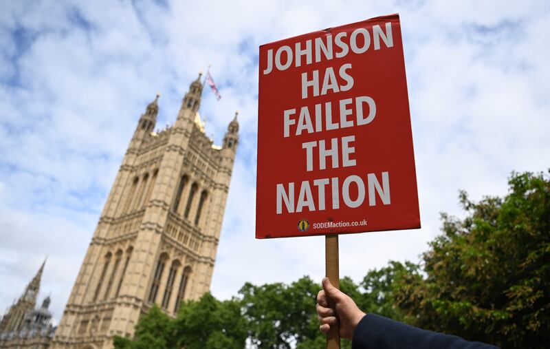 A protester holds up an anti-Boris Johnson placard outside parliament in London. EPA