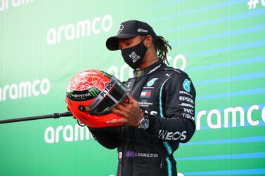 TOPSHOT - Winner Mercedes' British driver Lewis Hamilton holds the red helmet of former German Formula one champion Michael Schumacher that was offered to him by Mick Schumacher (unseen) on the podium after the German Formula One Eifel Grand Prix at the Nuerburgring circuit in Nuerburg, western Germany, on October 11, 2020. Lewis Hamilton equalled Michael Schumacher's record of 91 Formula One wins on on October 11, 2020 when he guided his Mercedes to a narrow, if measured, victory at Eifel Grand Prix. Schumacher's 21-year-old son Mick, a rising star and leader of the F2 series, presented Hamilton with a red helmet from his father's career collection. / AFP / POOL / Bryn Lennon