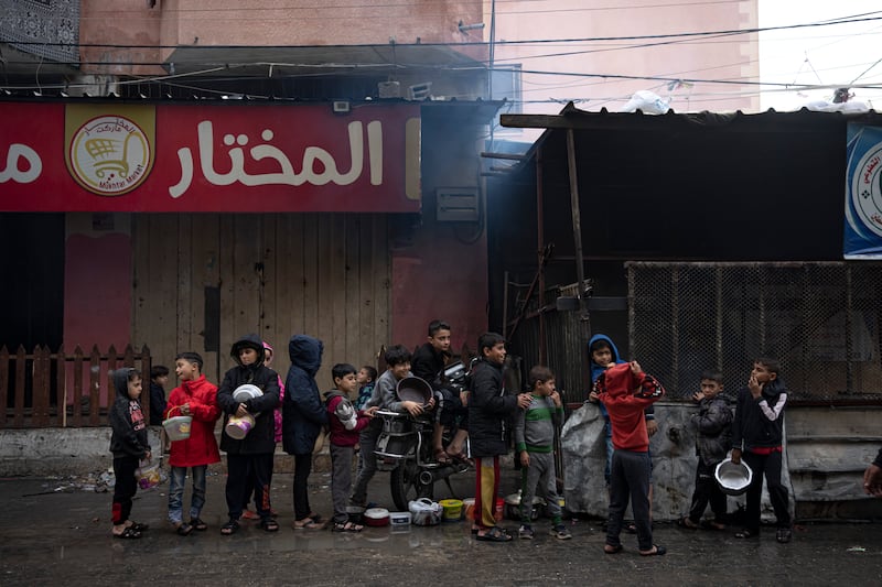Palestinian children wait in line for food in Rafah. AP