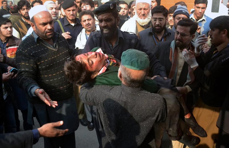 Hospital security guards carry a student injured in the shootout at a school under attacked by Taliban gunmen in Peshawar, Pakistan on Tuesday. Taliban gunmen stormed a military school in the northwestern Pakistani city, killing and wounding dozens, officials said, in the latest militant violence to hit the already troubled region. Mohammad Sajjad / AP Photo