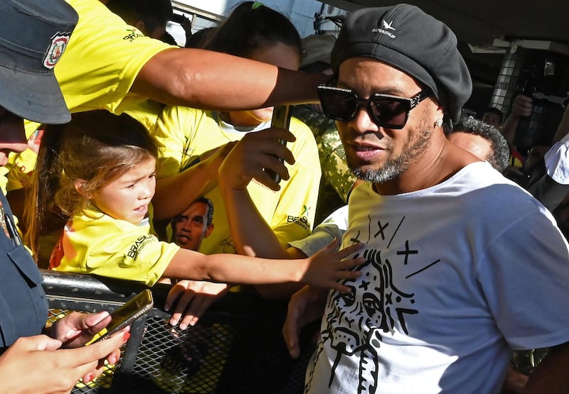 TOPSHOT - A girl stretches to touch Brazilian ex-football star Ronaldinho Gaucho upon his arrival at Silvio Pettirossi International Airport in Luque, near Asuncion, on March 4, 2020. Ronaldinho arrived in Paraguay to present his latest book "Genio en la Vida" and a health programme for girls and boys.
  / AFP / Norberto DUARTE
