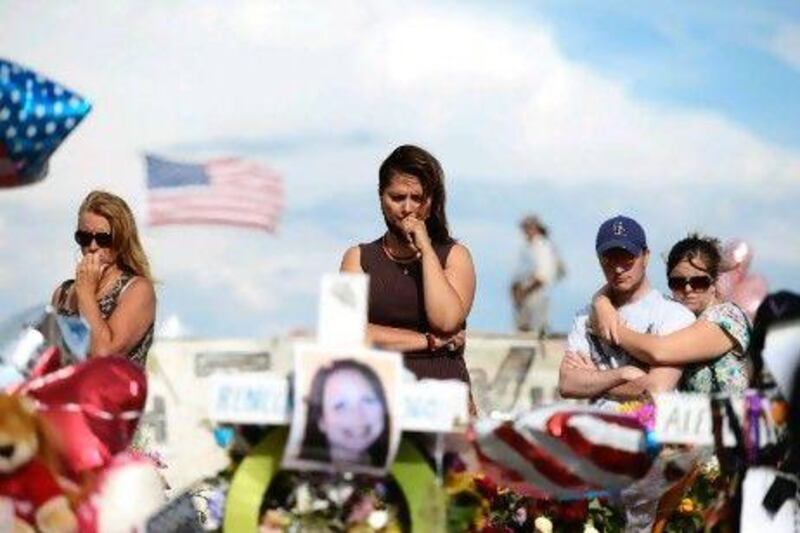 Cynthia Davis (centre) gets emotional as she visits a roadside memorial set up for victims opposite the Century 16 cinema where the shooting took place.