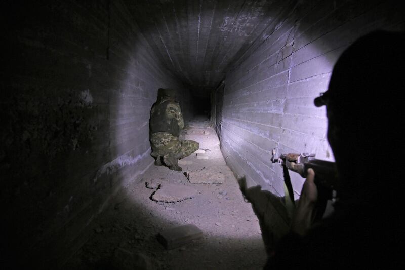Turkish-backed Syrian fighters inspect a tunnel, said to have been built by Kurdish fighters, in the Syrian border town of Tal Abyad. TAFP