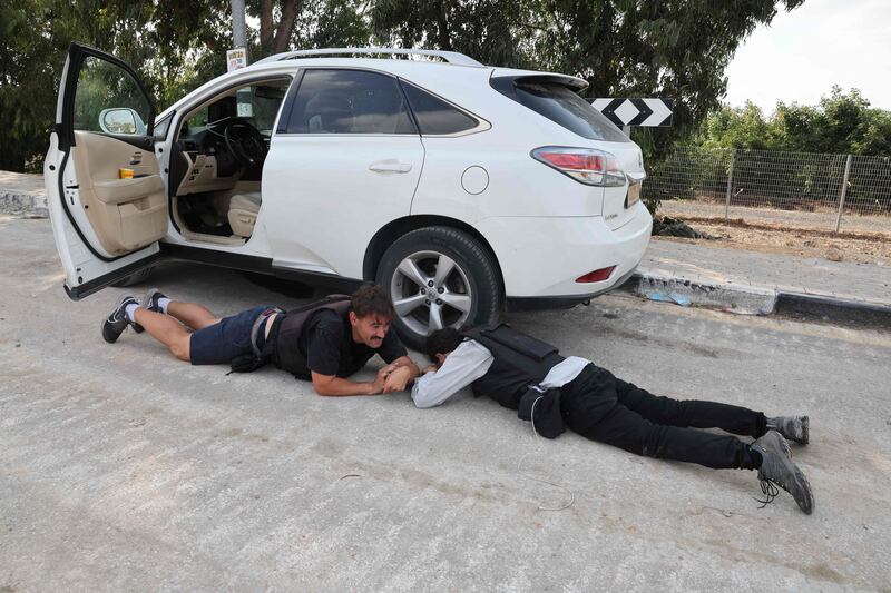 Israeli journalists take cover during a rocket attack from Gaza in the southern Israeli kibbutz of Kfar Aza near the border. AFP