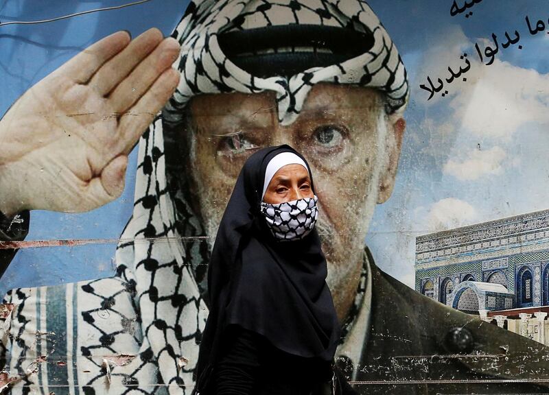 A woman covering her face walks past a poster depicting late Palestinian leader Yasser Arafat in Shatila Palestinian refugee camp, as the spread of coronavirus disease (COVID-19) continues, in Beirut suburbs, Lebanon. REUTERS