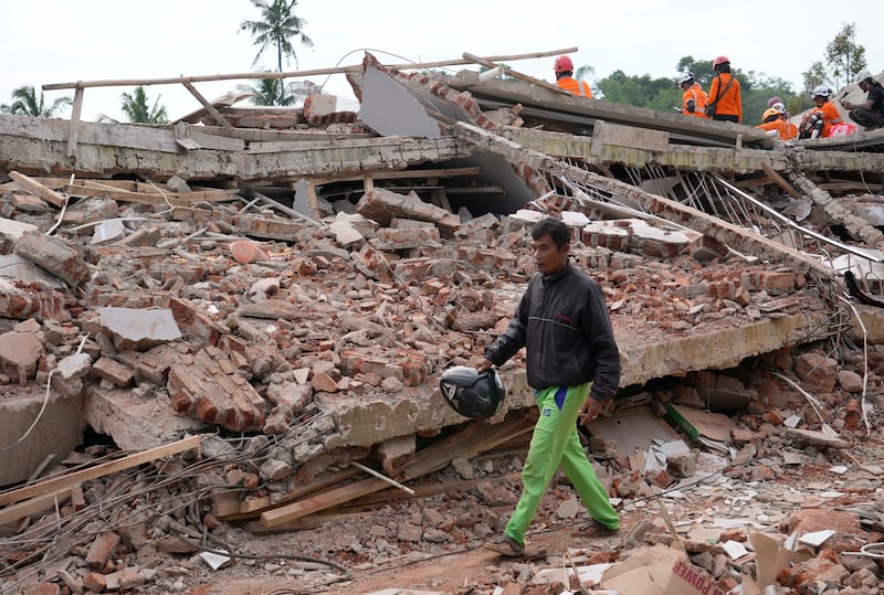 Enjot, 45, who lost his house and relatives, walks past the rubble of a building that collapsed in the earthquake in Cianjur, Indonesia. AP