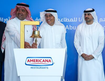 Americana Restaurants chairman Mohamed Alabbar, centre, and the company's vice chairman Abdulmalik Al Hogail ring the bell at the debut of the company's shares on the Abu Dhabi Securities Exchange as Hisham Malak, chairman of ADX, looks on. Victor Besa / The National