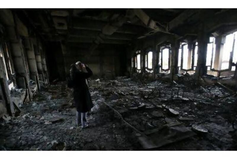 A woman takes pictures of the burnt house of Muammar Qaddafi inside Al Katiba military base, in Benghazi, yesterday.