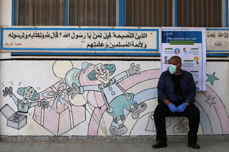 A Palestinian worker wearing a mask and gloves sits in an UNRWA-run school  in the central Gaza Strip. Reuters