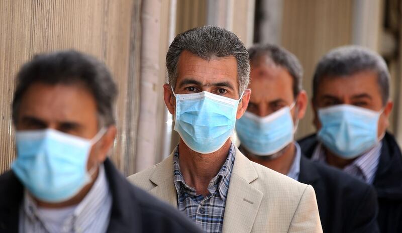 Libyans wearing protective face masks queue in front of a bank in the centre of the capital Tripoli, amidst the novel coronavirus pandemic crisis. AFP