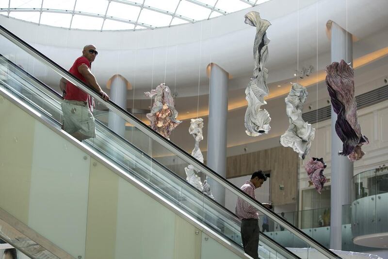 A shopper inspects the decorative sculptures as he makes his way down an escalator. Silvia Razgova / The National