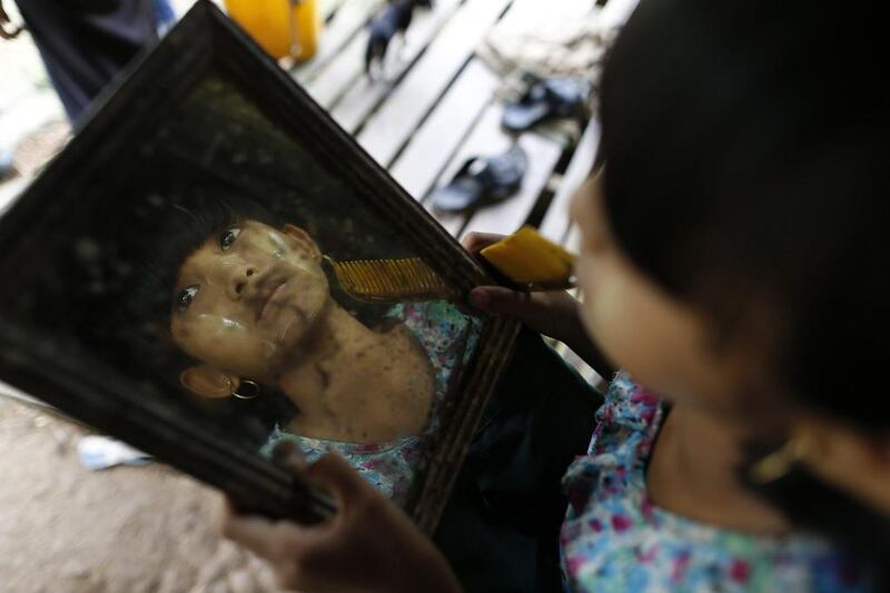 Cho Mar, an 11-year-old who hid in the jungle with her mother during an attack by Buddhist gangs, inspects the thanaka she had just put on her face at Thapyuchai village, outside of Thandwe in the Rakhine state. Soe Zeya Tun / Reuters
