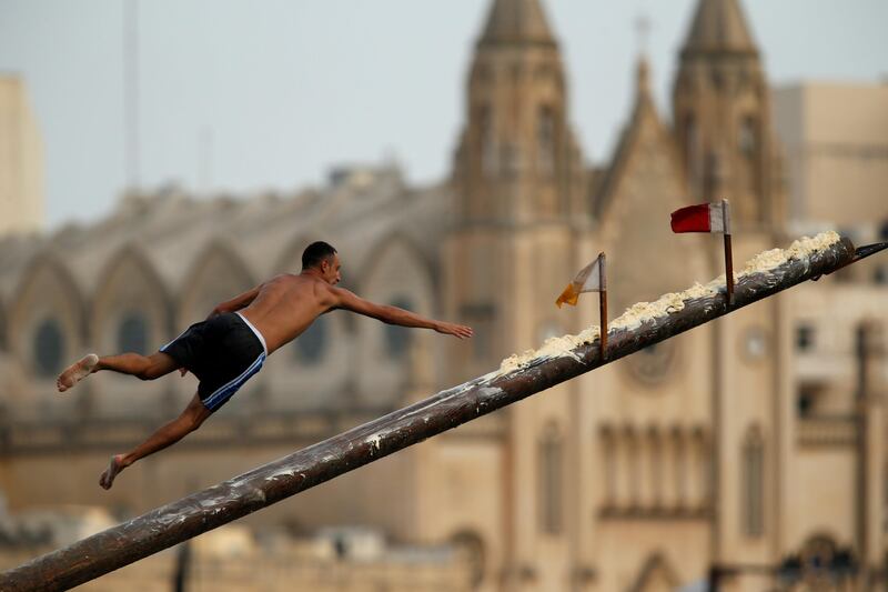 A competitor tries to grab a flag on the 'gostra', a pole covered in lard, as he falls off it during the celebrations for the religious feast of St Julian, patron of the town of St Julian's, Malta. Darrin Zammit Lupi / Reuters