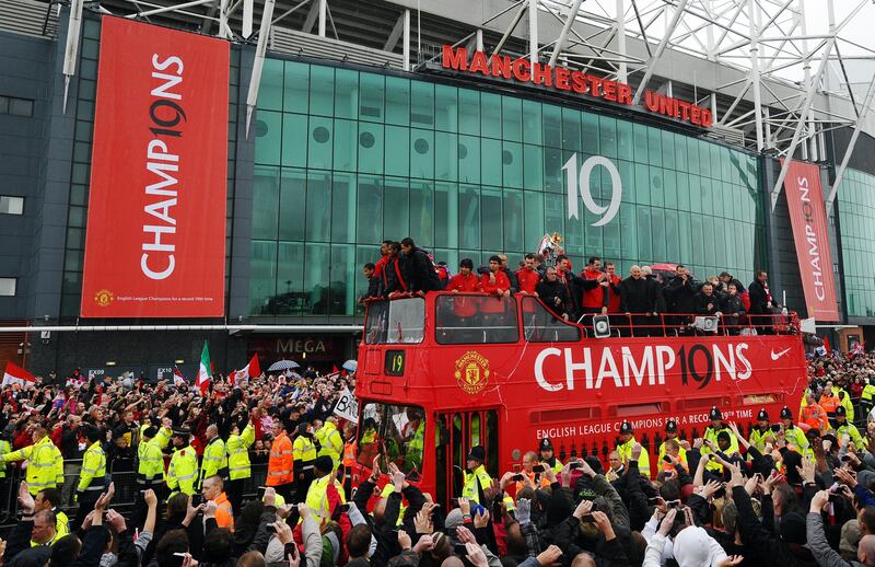 Manchester United supporters welcome a bus carrying the players and officials at Old Trafford in Manchester, north west England, on May 30 2011 as the team celebrate on the streets after winning the Premier league . AFP PHOTO/PAUL ELLIS